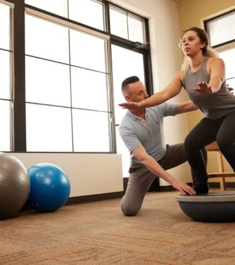 Physical therapist guiding a patient through a balance drill on a BOSU ball