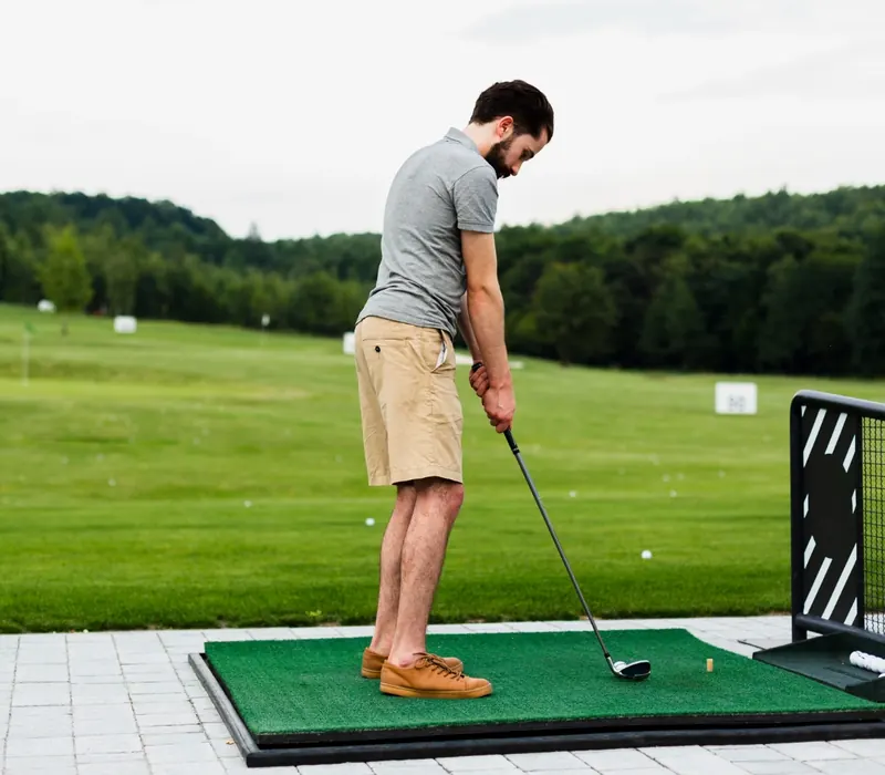 Golfer addressing the ball on a driving range mat